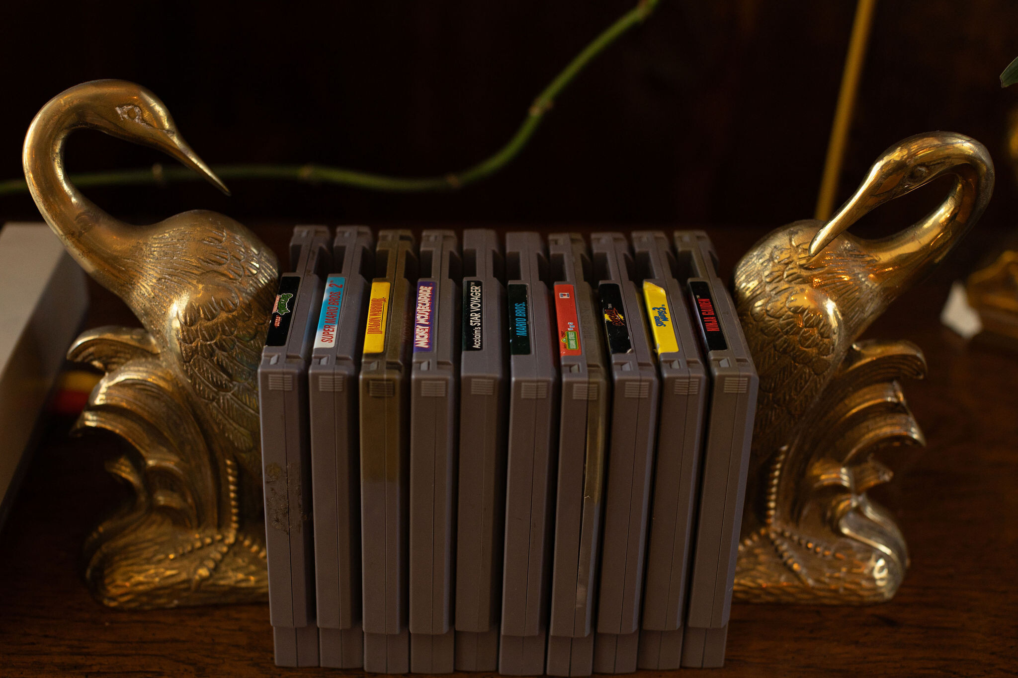 Brass crane bookends holding a row of vintage Nintendo cartridges