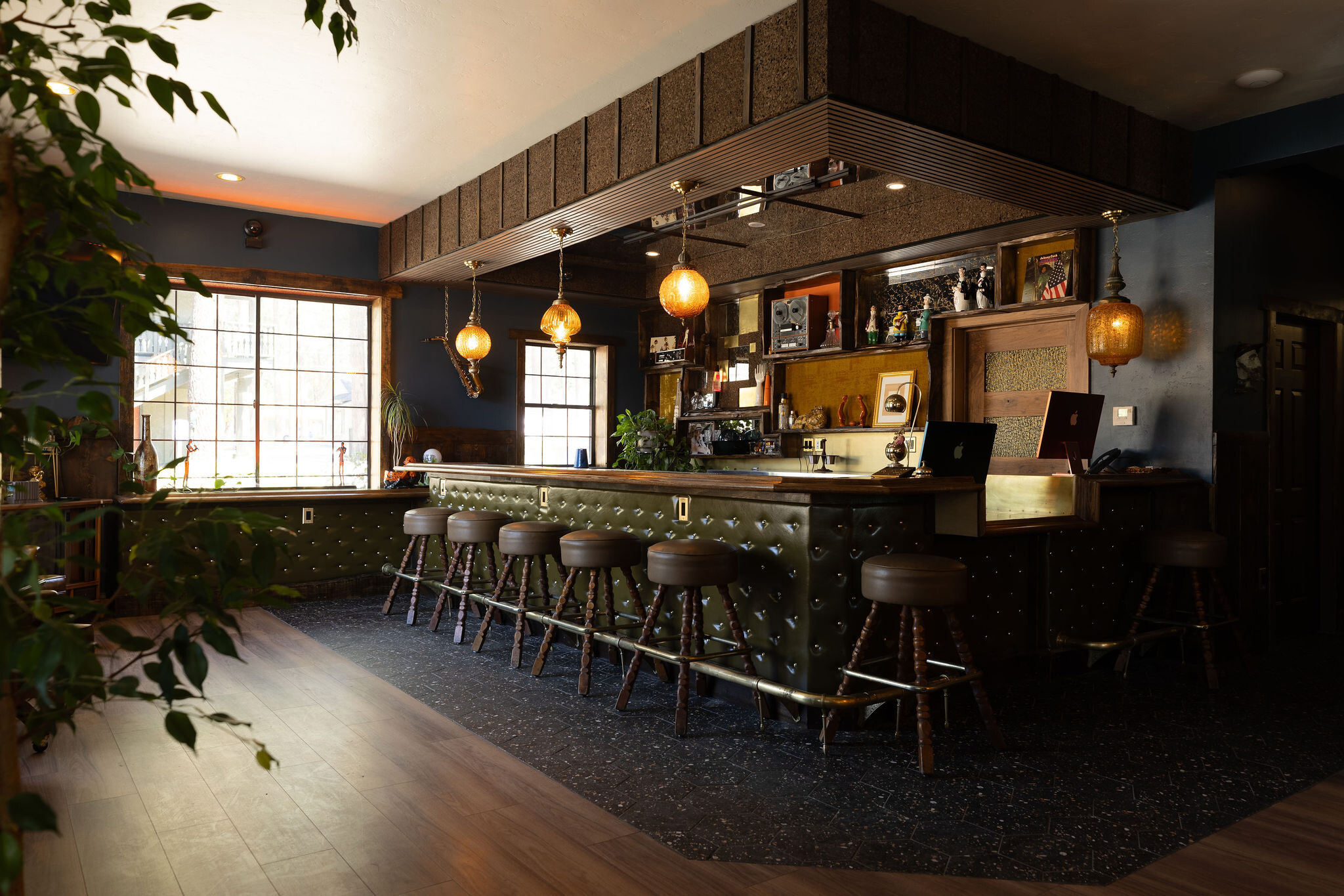 The Burgundy bar — wide moody shot with brass swag pendants and green tufted leather base